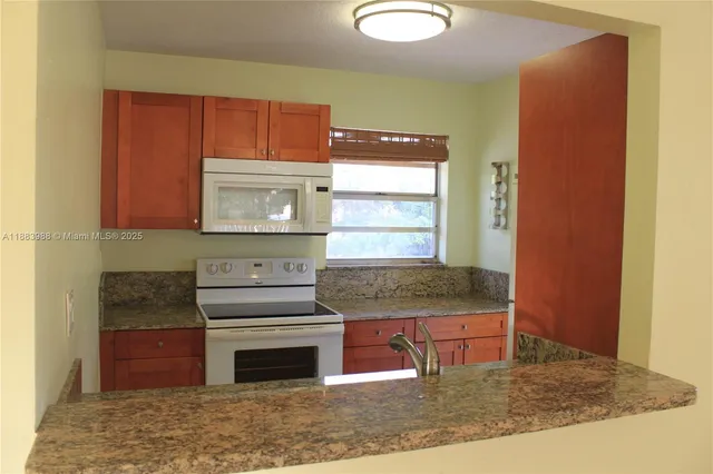 a kitchen with stainless steel appliances granite countertop a stove a sink and a microwave