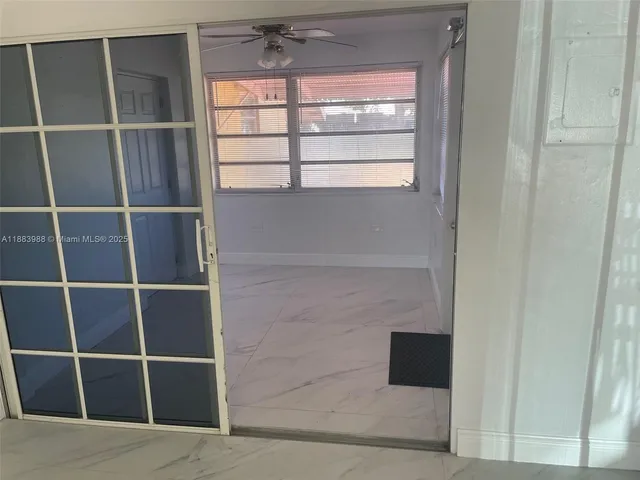 an empty room with windows and chandelier fan