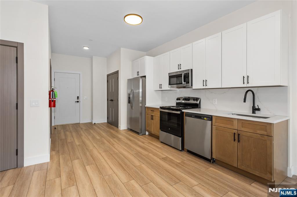 89 Mary Street, Unit 502 Paterson, NJ 07503 - Photo 6 of 13 a kitchen with granite countertop a refrigerator stove top oven and sink