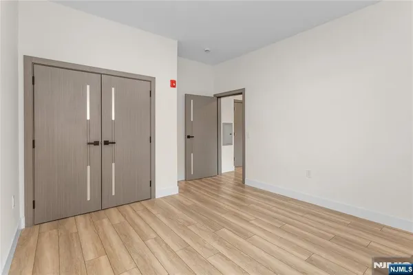 a view of a hallway with wooden floor and closet area