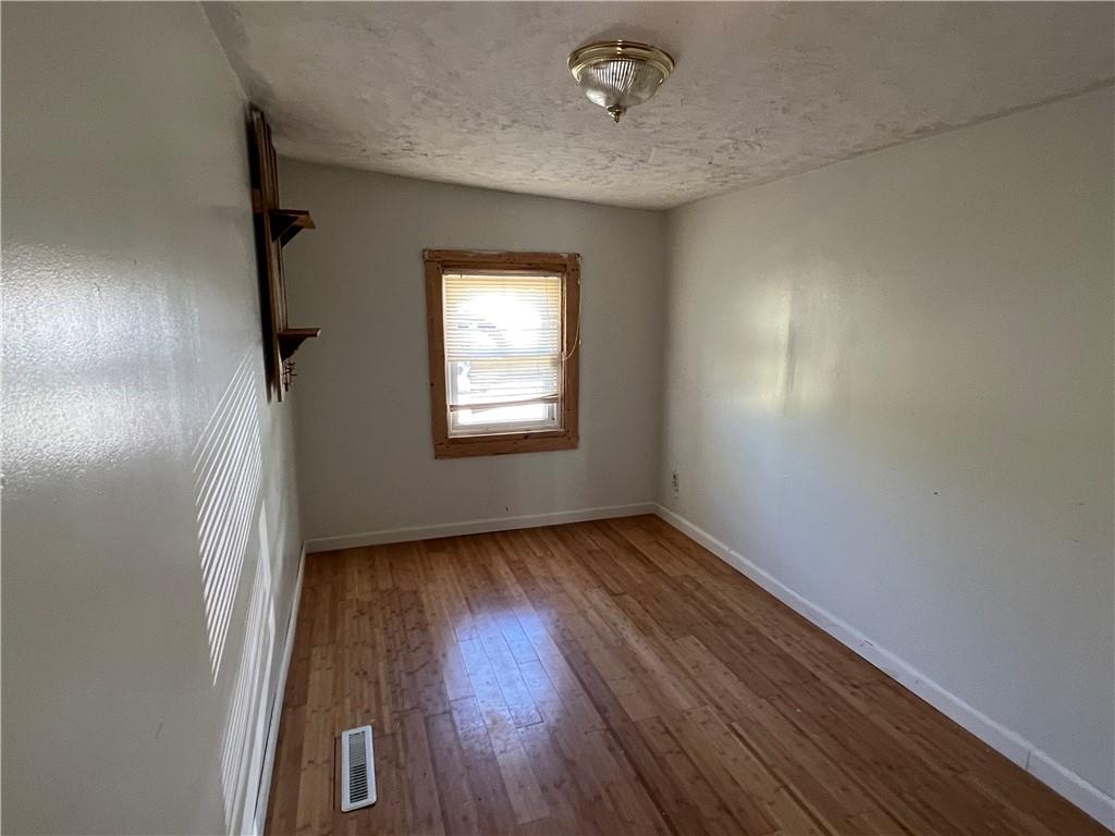 151 Oak Forest Road Brave, PA 15316 - Photo 7 of 16 an empty room with wooden floor and windows