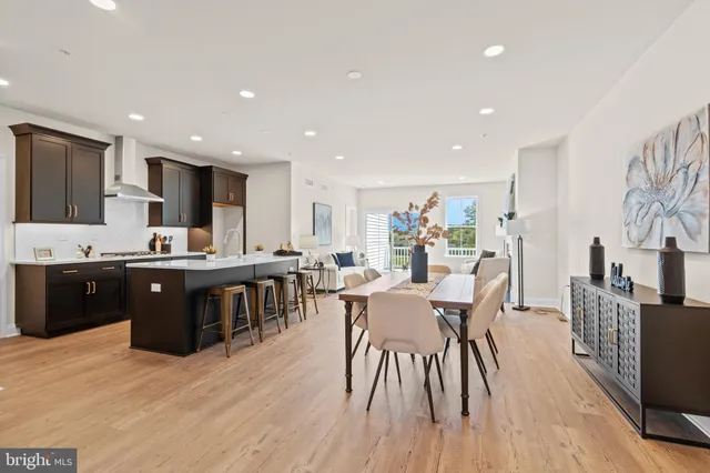 a living room with stainless steel appliances kitchen island granite countertop a table chairs and a computer on a table