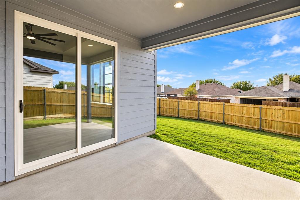 1640 West Wintergreen Road Lancaster, TX 75134 - Photo 29 of 37 Covered patio with a concrete surface, sliding glass doors, and a wood fence enclosing a grass lawn