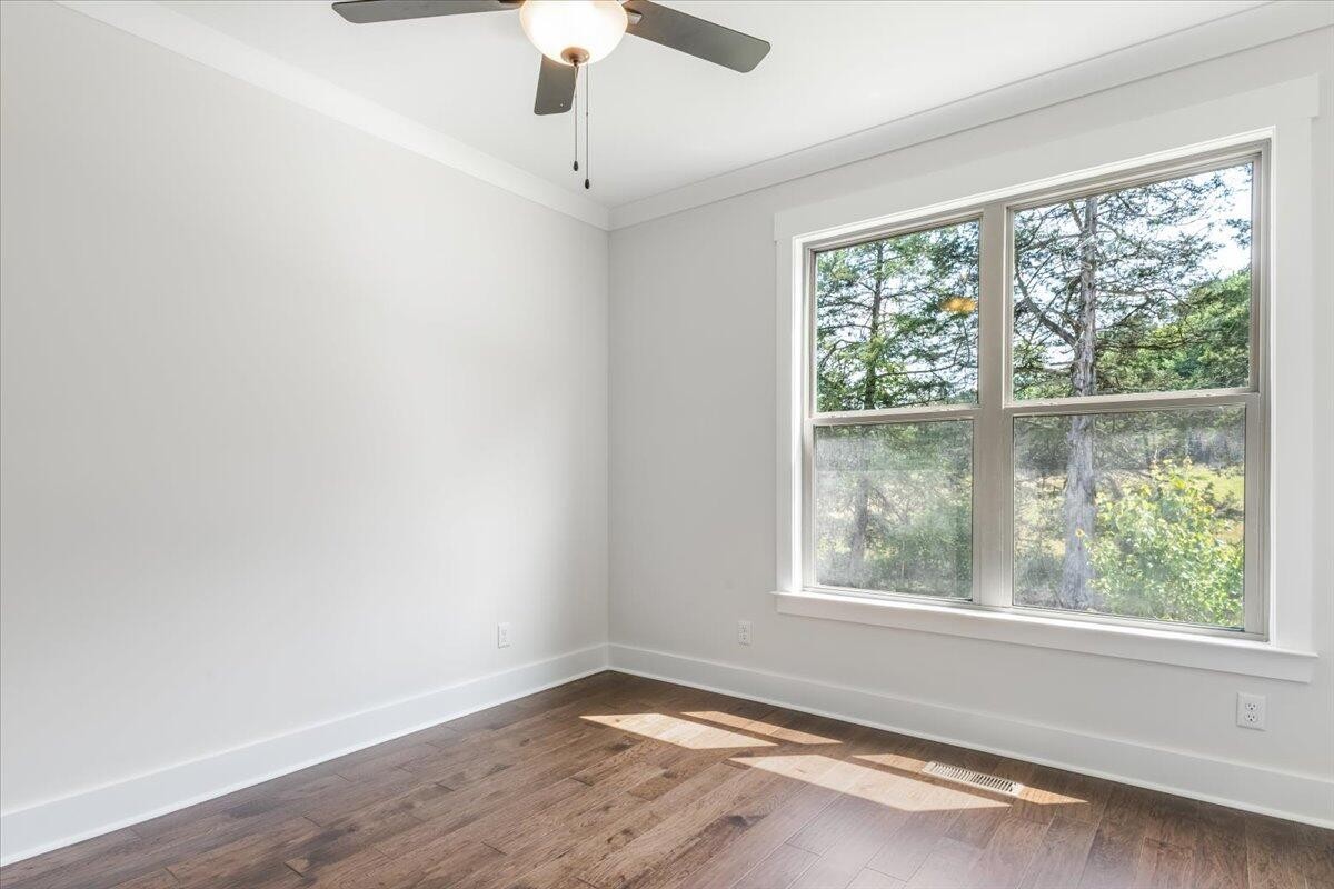 7391 Gamble Road Georgetown, TN 37336 - Photo 17 of 27 an empty room with wooden floor chandelier fan and windows
