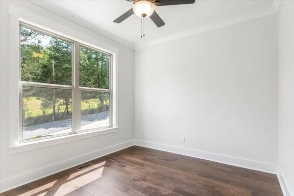 an empty room with wooden floor fan and windows