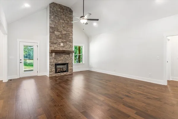 an empty room with wooden floor a fireplace and windows
