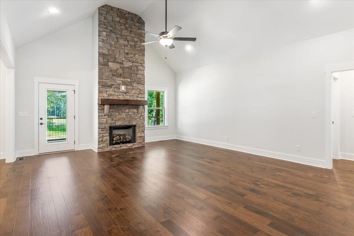 7391 Gamble Road Georgetown, TN 37336 - Photo 4 of 27 an empty room with wooden floor a fireplace and windows
