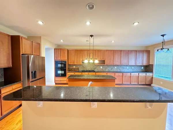 a kitchen with stainless steel appliances granite countertop a refrigerator a sink and a stove