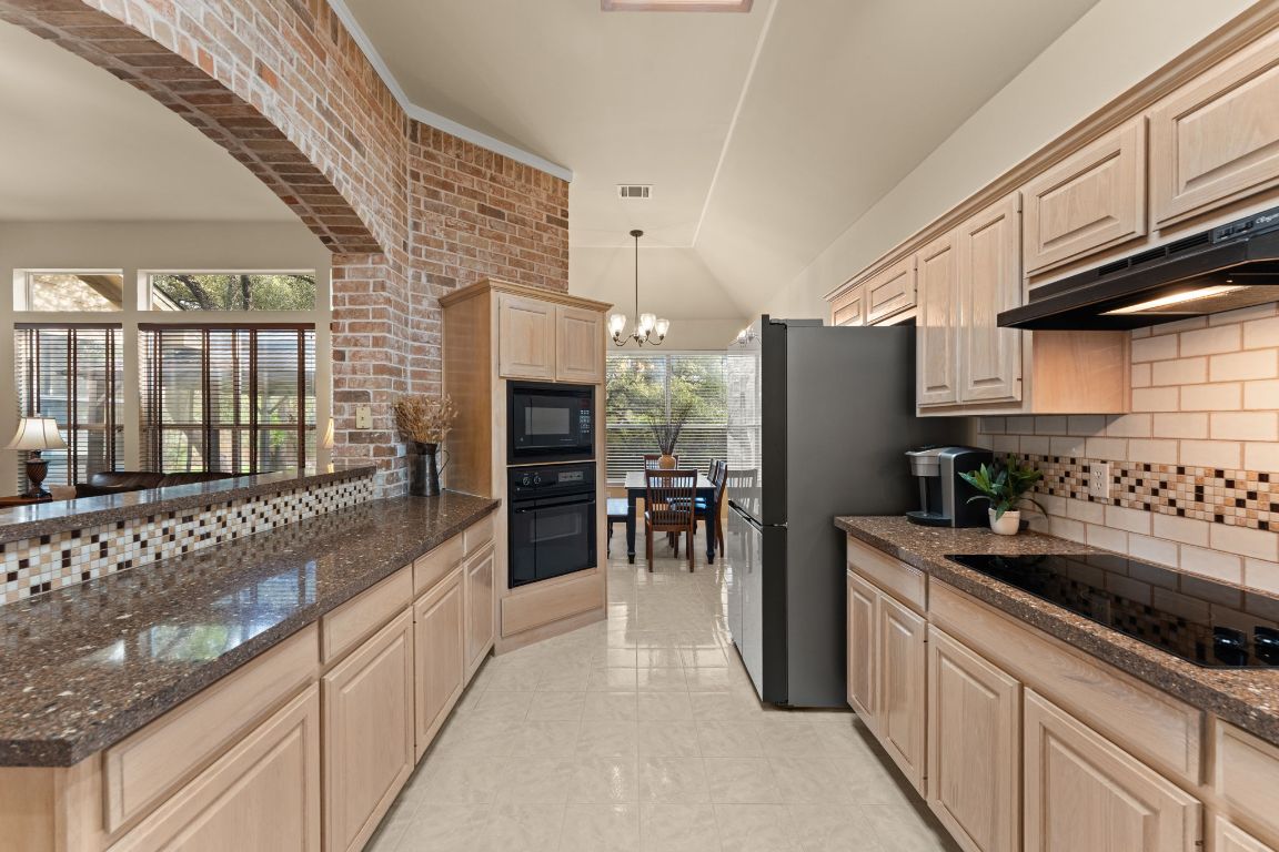 603 Flamingo Boulevard Lakeway, TX 78734 - Photo 5 of 40 The kitchen has a large amount of cabinets and a pantry with the added bonus of a brick accent wall.
