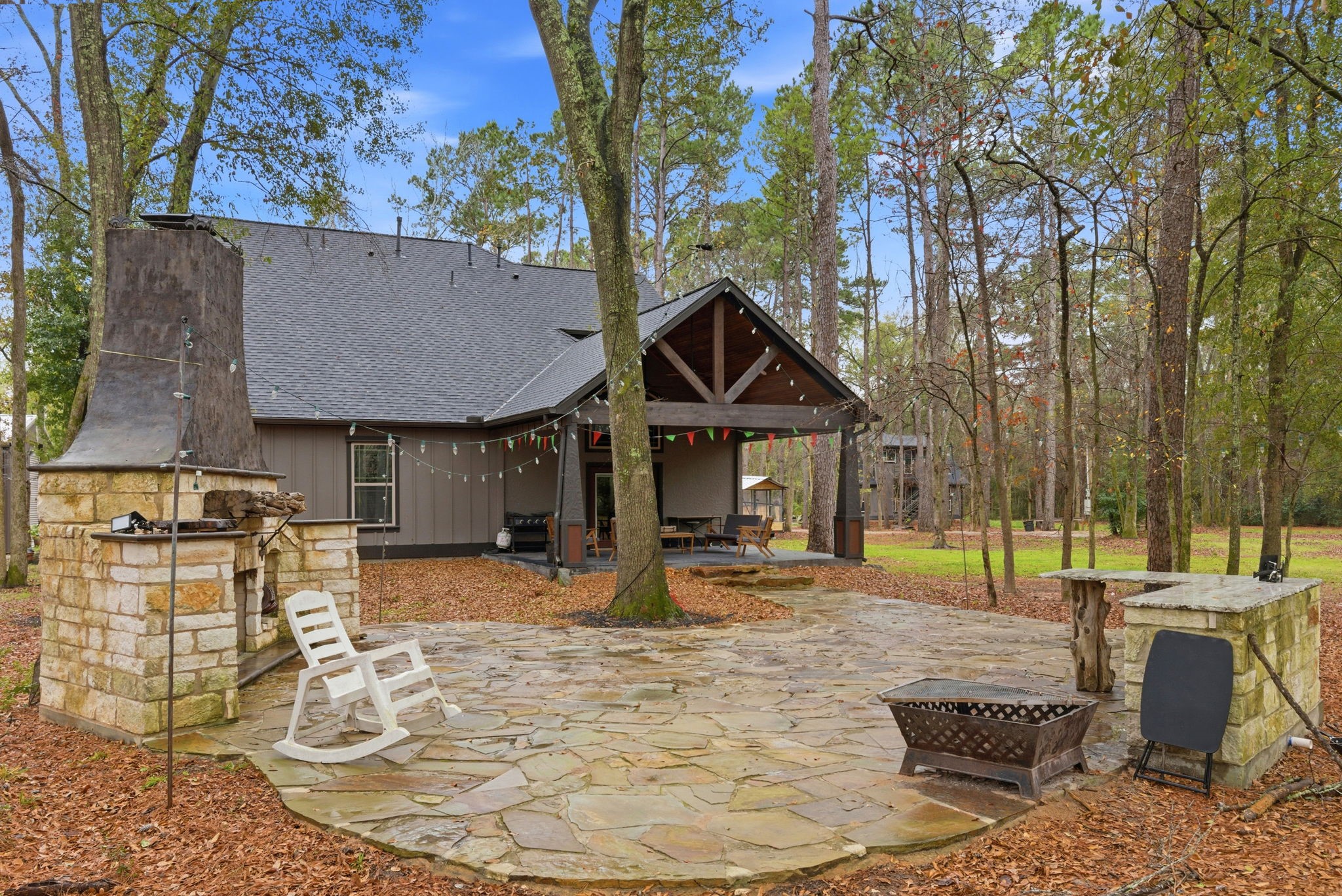 1480 Traylor Road Conroe, TX 77304 - Photo 18 of 25 Spacious backyard with stone patio, covered outdoor area, and designated space ideal for a future outdoor kitchen, surrounded by mature trees.