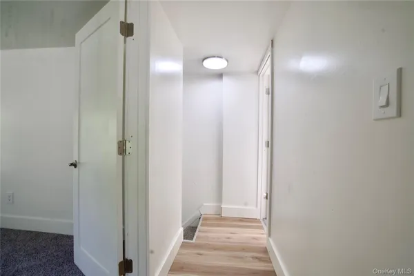 a view of a hallway with wooden floor and a bathroom