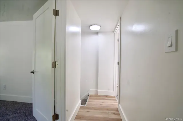 a view of a hallway with wooden floor and a bathroom