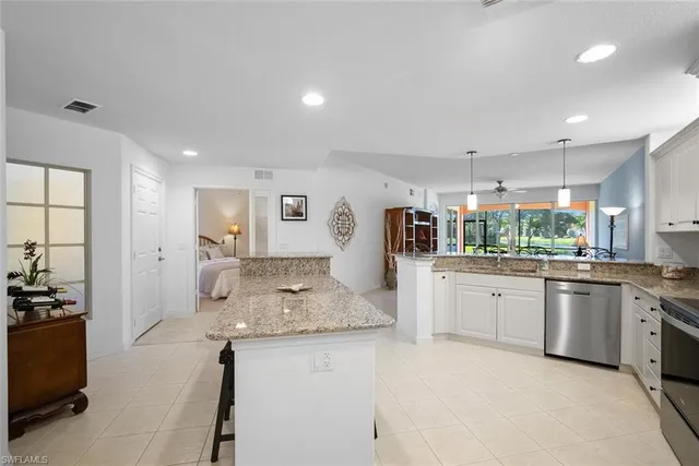 a kitchen with stainless steel appliances kitchen island granite countertop a dining table chairs and a refrigerator