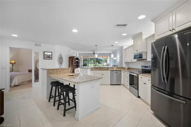 a kitchen with stainless steel appliances kitchen island granite top and refrigerator