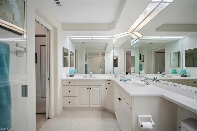 a view with double vanity sink a mirror a lamp and vanity