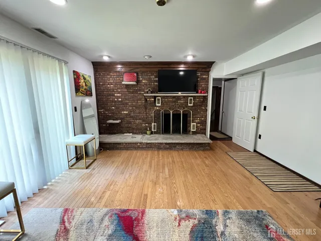 a view of an empty room with wooden floor and a fireplace