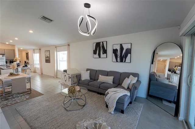 a living room with patio furniture and kitchen view