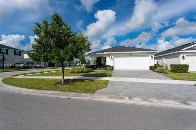 a view of a white house next to a yard with big trees