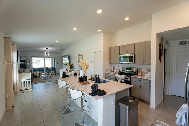 a kitchen with a sink a refrigerator and chairs