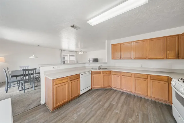 a kitchen with stainless steel appliances granite countertop wooden cabinets a sink a stove a dining table and chairs