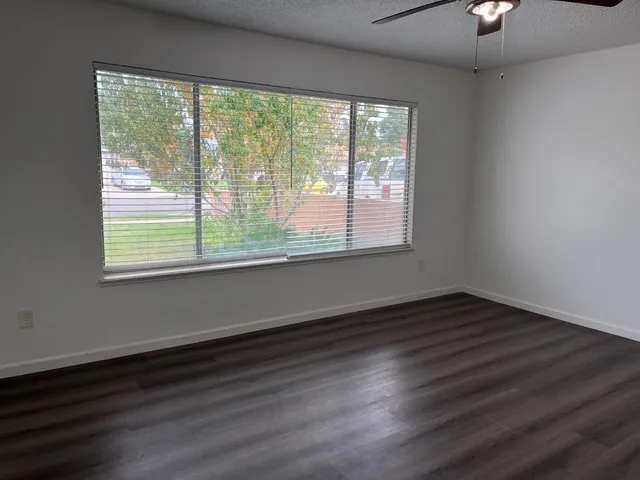 a view of an empty room with wooden floor and a window