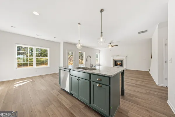 a kitchen with stainless steel appliances granite countertop a sink a stove and a wooden floor
