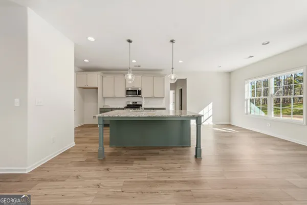 a view of kitchen with stainless steel appliances granite countertop a stove a refrigerator a sink dishwasher with a dining table and chairs with wooden floor