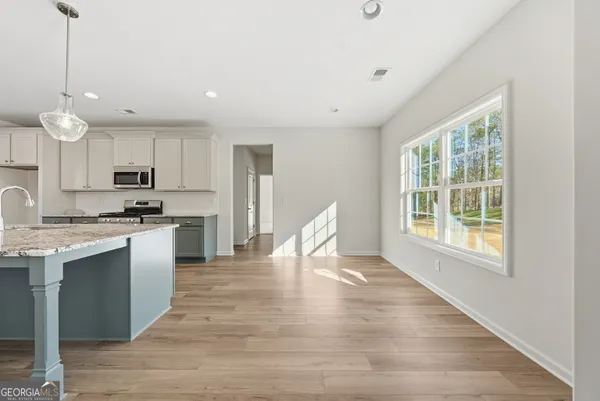 a kitchen with granite countertop a stove a sink dishwasher a refrigerator and white cabinets with wooden floor