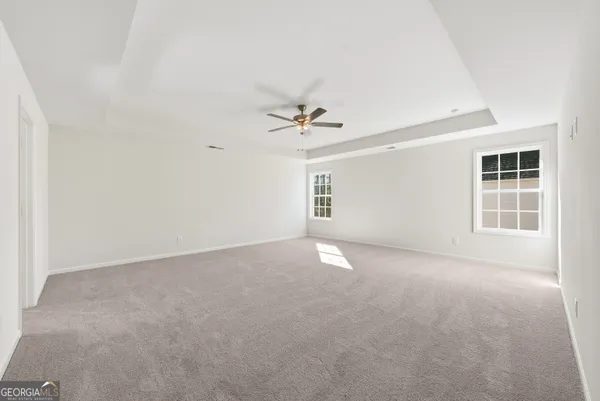 an empty room with windows and ceiling fan