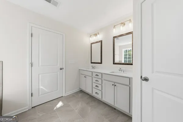 a spacious bathroom with 2 sink and a mirror