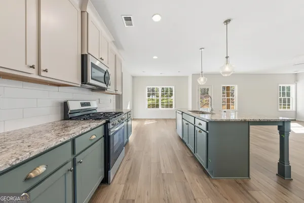 a large kitchen with stainless steel appliances granite countertop a stove and a wooden floors