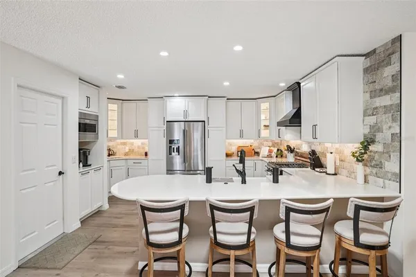 a kitchen with white cabinets and chairs