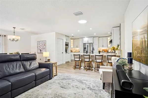 a living room kitchen with a dining table wooden floor and a kitchen view