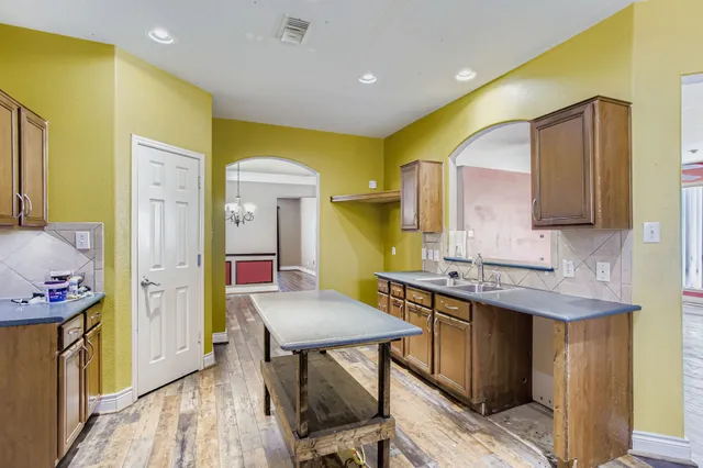 a kitchen with a sink a stove cabinets and wooden floor