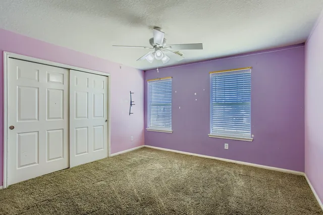 an empty room with a ceiling fan and a window