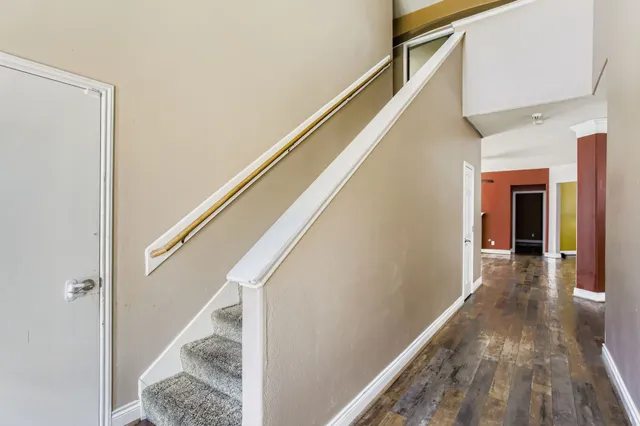 a view of a hallway with wooden floor and staircase