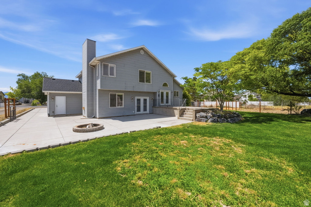 3732 Campbell Road Tooele, UT 84074 - Photo 41 of 69 Expansive backyard featuring a manicured lawn, concrete patio with a built-in fire pit, and mature trees