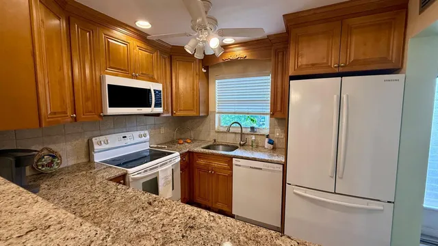 a kitchen with stainless steel appliances granite countertop a refrigerator a sink a stove a microwave and island