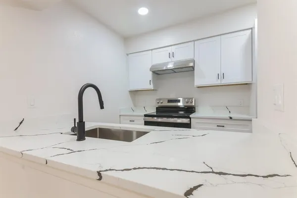 a kitchen with stainless steel appliances kitchen island a sink a stove and white cabinets