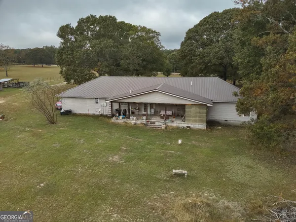 a aerial view of a house next to a lake with a large trees