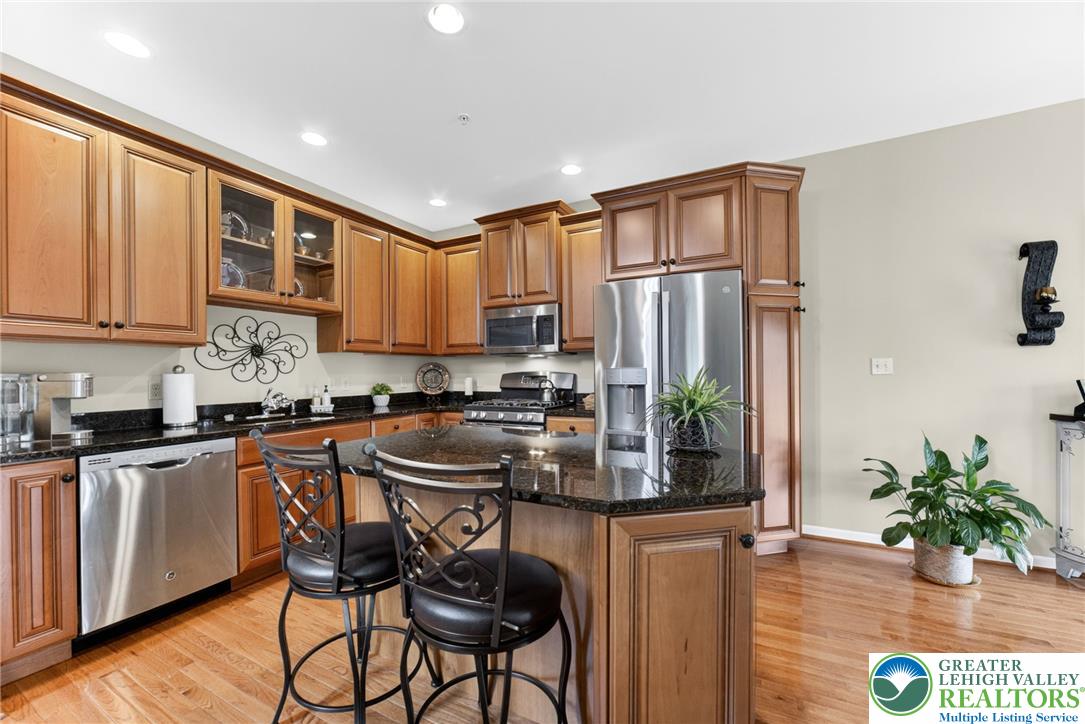 5440 Spring Ridge Drive West Macungie, PA 18062 - Photo 8 of 40 A chef's kitchen showcasing rich wood cabinetry, granite countertops, and modern stainless steel appliances.