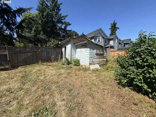 a view of a yard with plants and wooden fence