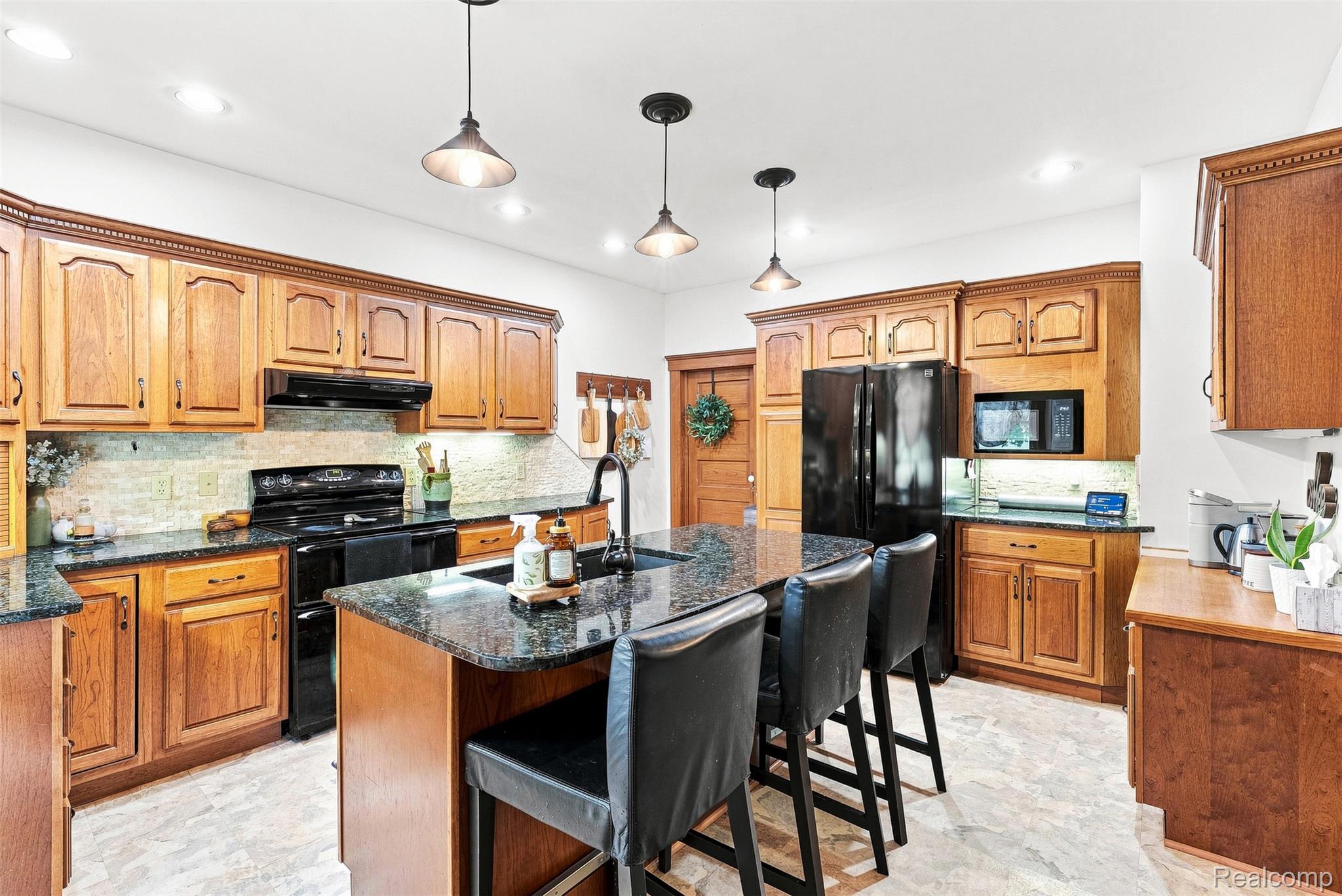 2971 Huron Line Road Cass City, MI 48726 - Photo 11 of 63 Kitchen featuring wood cabinetry, dark countertops, a central island with seating, pendant lighting, and black appliances