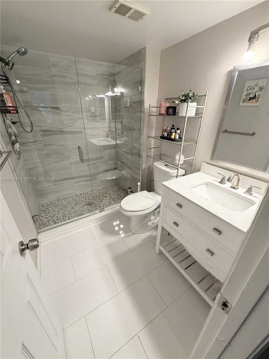 8741 Wiles Road, Unit 204 Coral Springs, FL 33067 - Photo 7 of 16 a bathroom with a double vanity sink toilet mirror and shower