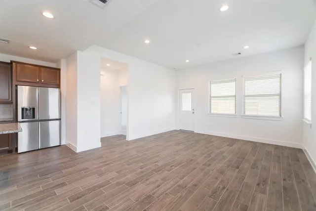 a view of empty room with wooden floor and window