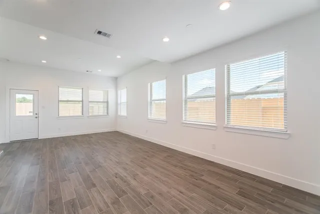 an empty room with wooden floor and windows
