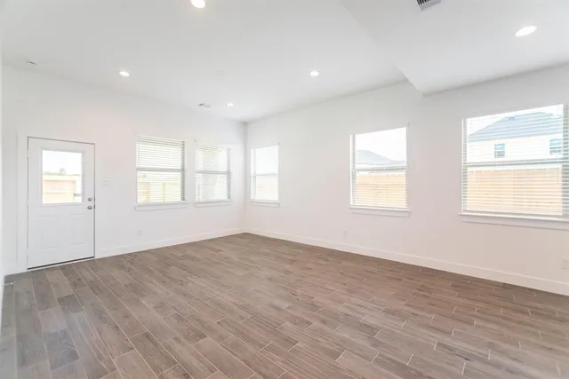 an empty room with wooden floor and windows