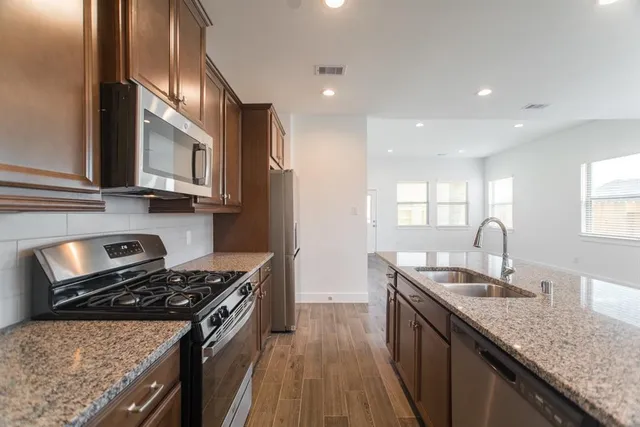 a kitchen with stainless steel appliances granite countertop a stove a sink dishwasher and a refrigerator