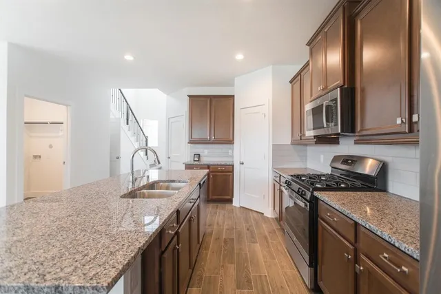 a kitchen with stainless steel appliances granite countertop a stove a sink and a microwave