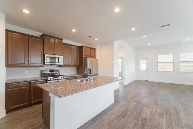 a kitchen with stainless steel appliances granite countertop a sink stove and refrigerator